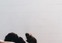 필라테스, 몸과 마음의 균형을 잡아주는 현대인의 필수 운동 woman in black tank top and black leggings lying on black floor