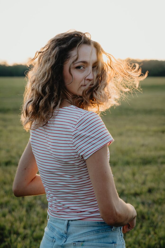 Woman with curly hair in a field at sunset