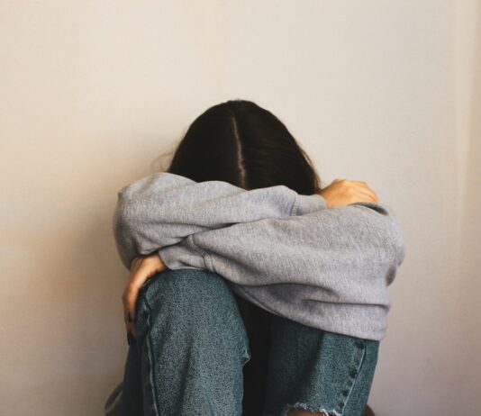 “담배 15개비보다 해롭다”… 당신을 서서히 죽이는 보이지 않는 전염병 ‘외로움’ a woman sitting on the floor with her arms wrapped around her head