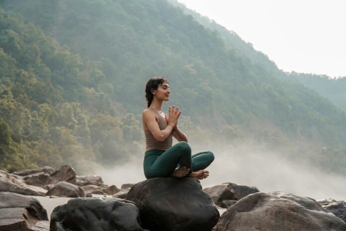 Photo by Sumit Bisht a woman sitting on top of a rock next to a river