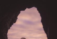 바쁜 일상 속 스트레스, 똑똑하게 풀고 건강 챙기는 생활 습관 Sea stack and beach visible through a dark cave opening.